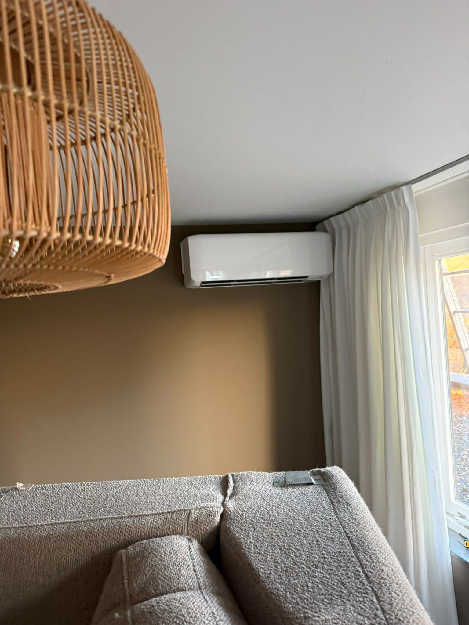 Witte wandunit tegen een beige wand in een woonkamer, met een rotan hanglamp op de voorgrond