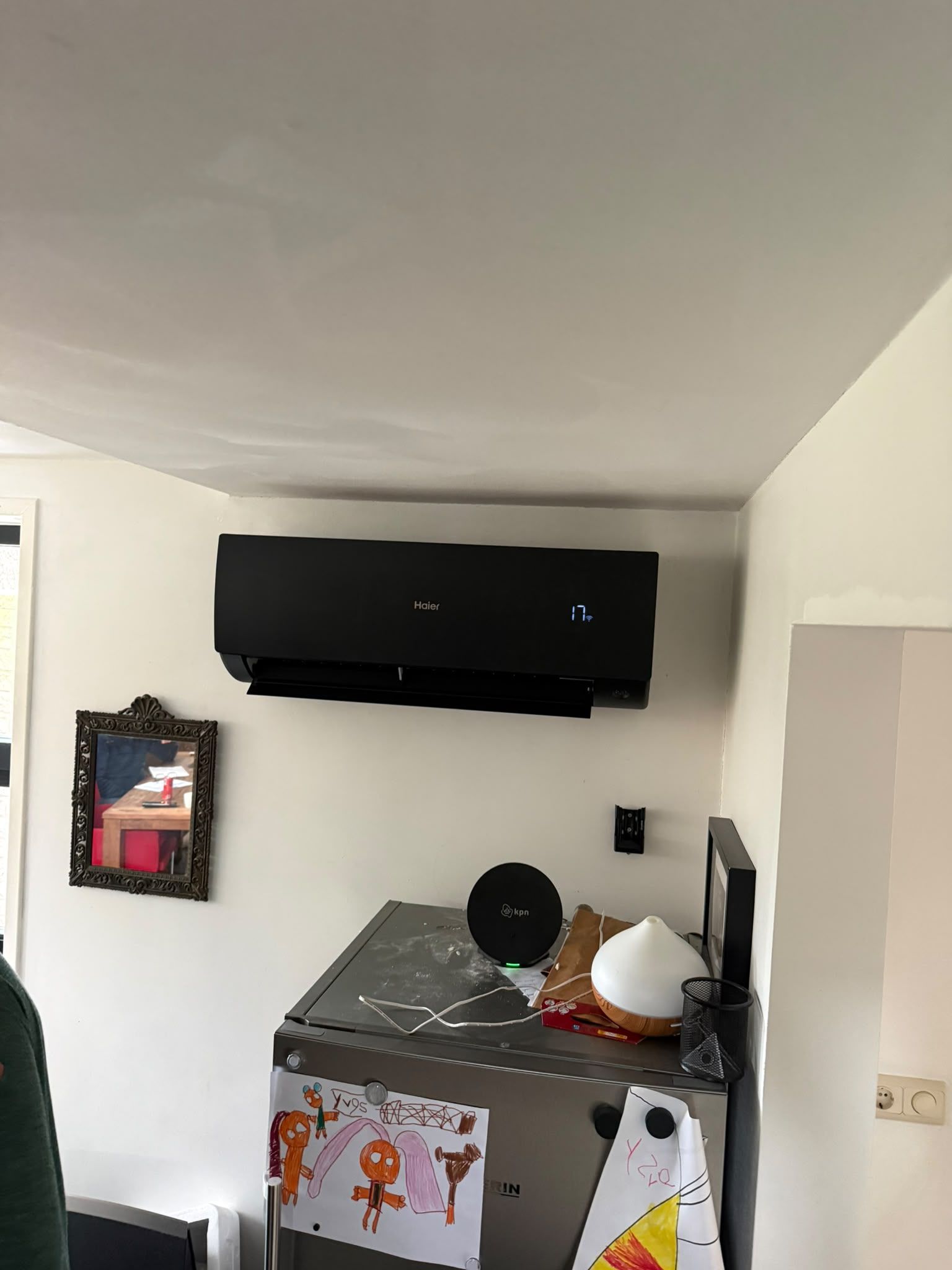 Zwarte Haier-wandunit tegen een witte wand, met display aan