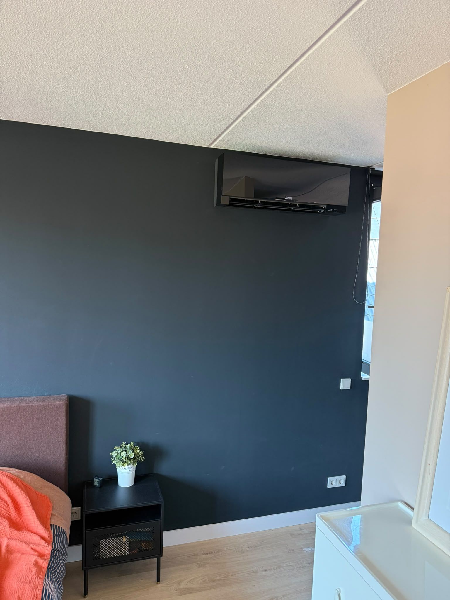 Zwarte wandunit hoog tegen een donkerblauwe slaapkamerwand