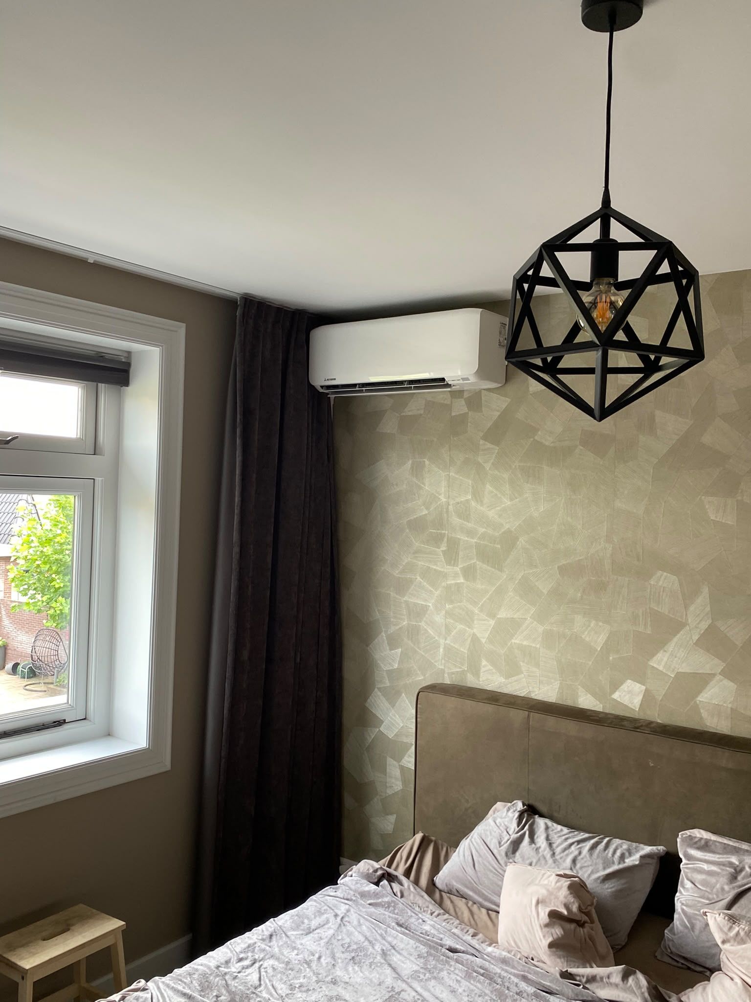 Witte wandunit in een slaapkamer, naast een raam en een zwarte designhanglamp