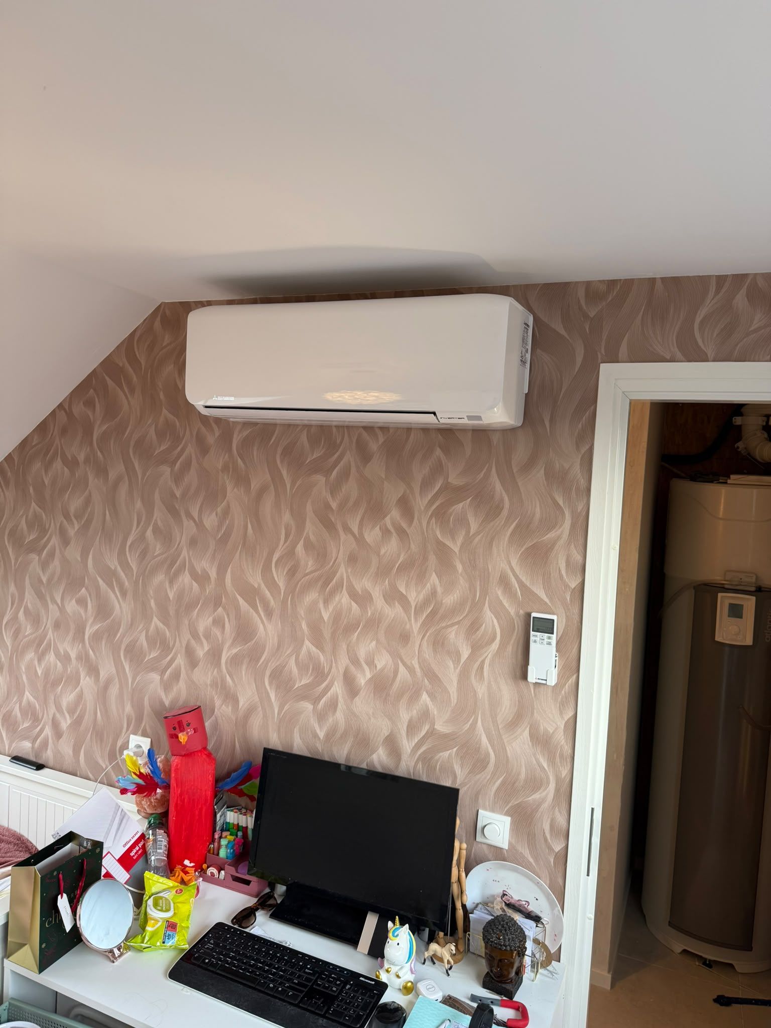 Witte wandunit op zolder tegen een behangwand met motief, met bedieningspaneel aan de muur