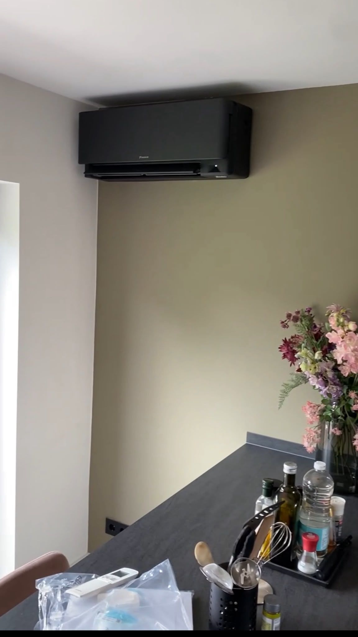 Zwarte wandunit in een keuken, hoog tegen een beige wand boven het aanrecht