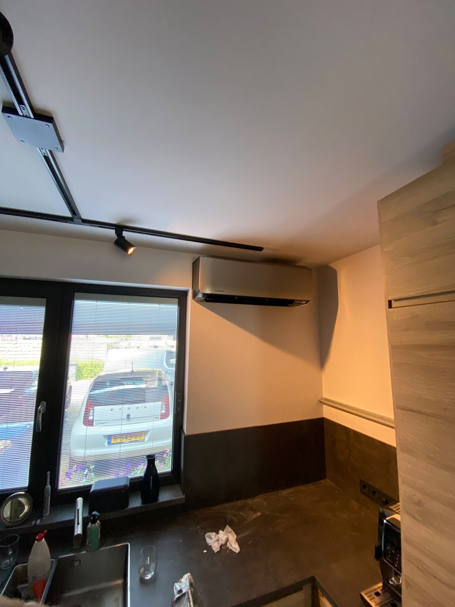 Witte wandunit in een keuken, naast een raam en boven het keukenblok